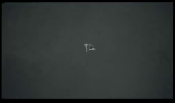 Chase-camera view of a grey fighter banking through a dark overcast sky