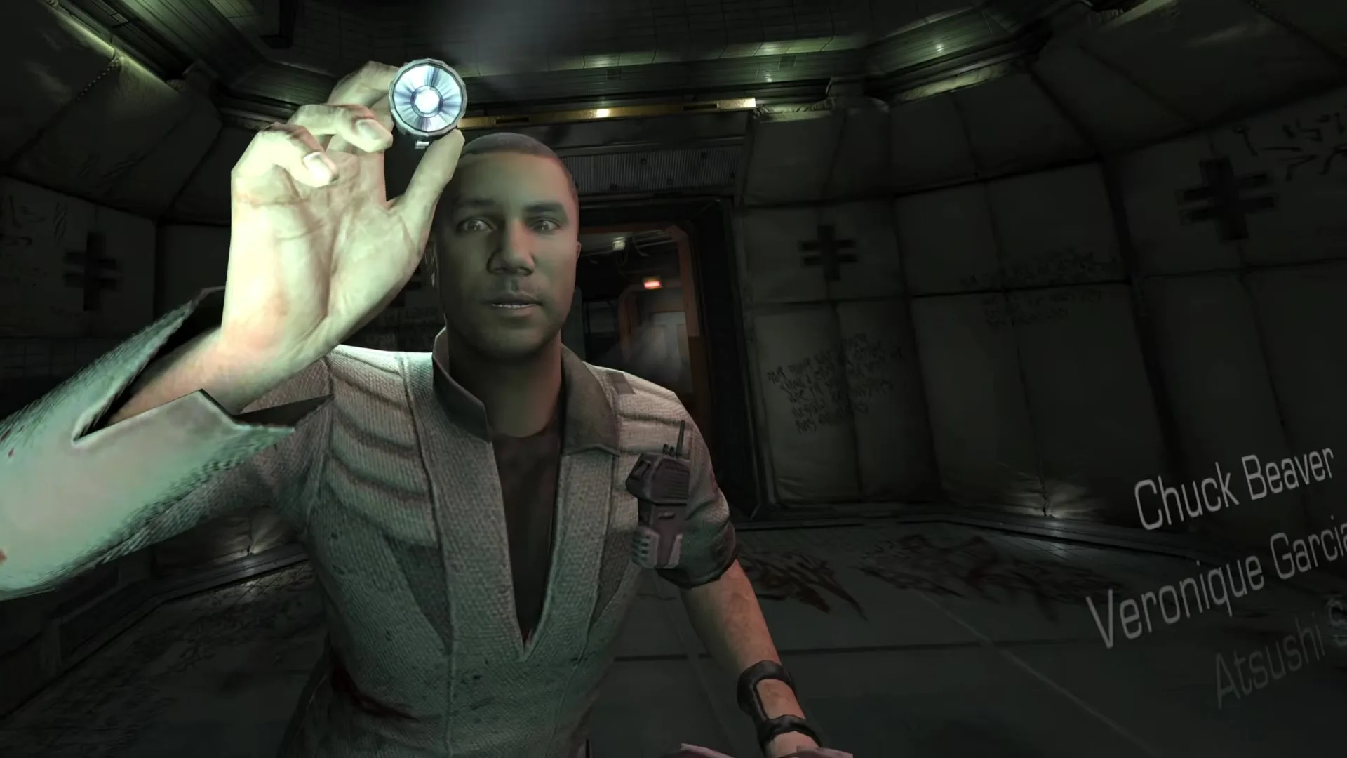 A hand holds up a small glowing device in front of a man's face, with Dead Space 2's opening credits floating to the right