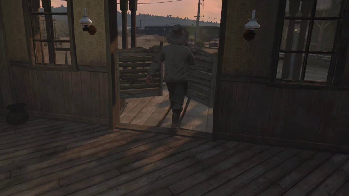 A cowboy walks out through saloon swing doors from a dim wooden interior