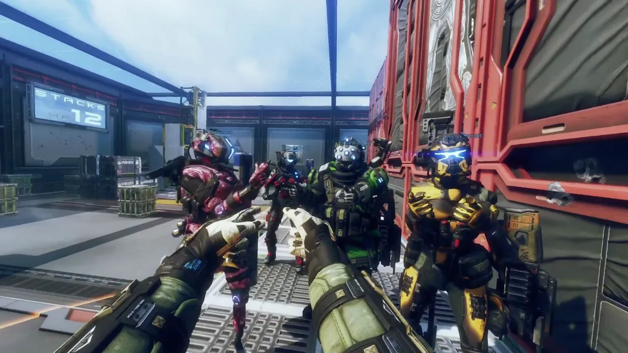 First-person view holding a rifle with two gloved hands, beside four other pilots in red, green and yellow armor